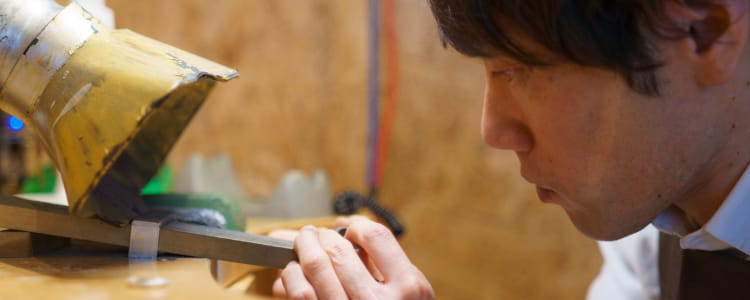 作業台の上で細かい調整をしており、手作りの精密な工程が伝わる場面。