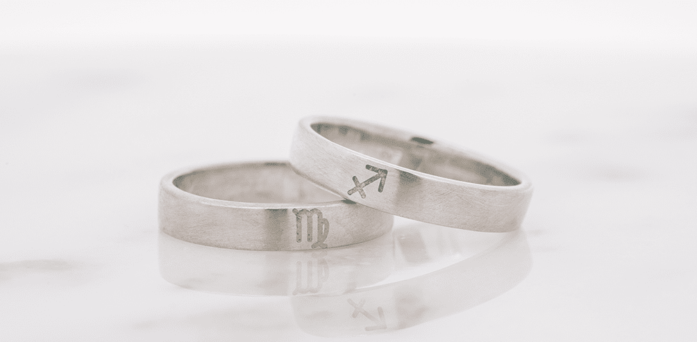 星座の彫り加工に黄色のエマーユが施されたリングと緑のエマーユが施されたリングが重なっている。